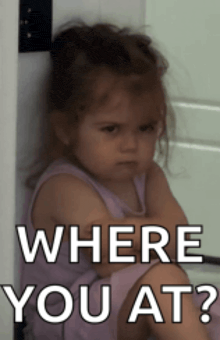 a little girl is sitting next to a door with the words where you at