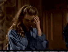 a woman with a ring on her finger holds her hand to her forehead