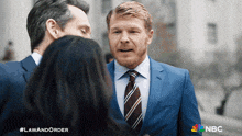 a man in a suit and tie is talking to a woman in a nbc ad