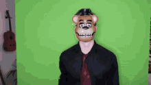a man in a black shirt and red tie is wearing a teddy bear mask on his head .