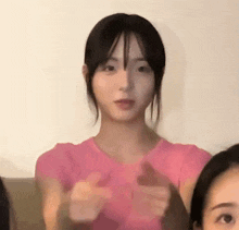 a woman in a pink shirt is giving a thumbs up sign while sitting next to another woman .
