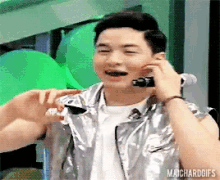 a man wearing a silver vest is talking on a cell phone .