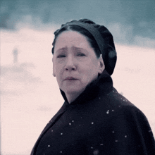 a woman wearing a black cape and a black hat is crying