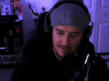 a man wearing headphones and a beanie says " ayy man " in red