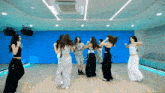a group of women are dancing in a room with a blue wall behind them