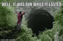 a person is standing in the woods with their arms outstretched in front of a cave .