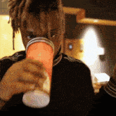 a man with dreadlocks is drinking from a cup