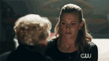 a woman in a black shirt is talking to another woman in a dark room .