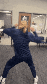 a woman in a blue sweatshirt is dancing in front of a door
