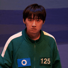 a man wearing a green jacket with the number 125 on the front