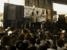 a crowd of people are gathered in front of a stage with a sign that says " a un peso " on it