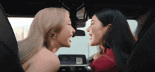 two women are kissing in the back seat of a car while laughing