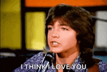 a young man is singing into a microphone and says `` i think i love you '' .