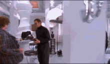 a man in a black turtleneck is holding a camera in a room