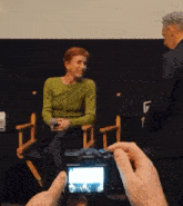 a man is taking a picture of a woman in a green sweater