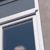 a man is looking out of a window with a blue sky behind him