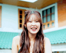 a young woman with braids in her hair is smiling in front of a building