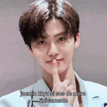 a young man is holding his finger to his lips and says jaemin kkyu si sos de more únicamente