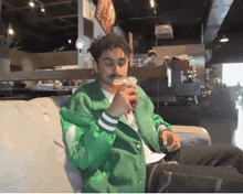 a man in a green jacket is drinking a beer