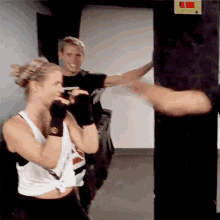a woman wearing a white tank top with the word reebok on it is boxing