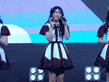 a girl in a red and white dress stands in front of a large screen