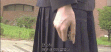 a person in a school uniform is holding something in their hand in front of a building .