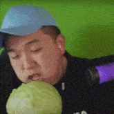 a man wearing a blue hat is eating a cabbage with his eyes closed