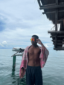 a shirtless man is standing in the water wearing sunglasses
