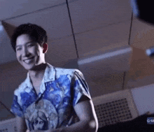 a young man in a blue shirt is dancing in a room with a ceiling .