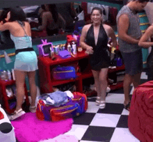 a group of people are standing in a room with a checkered floor and a woman in a black dress .