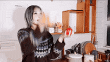 a woman in a sweater is holding a red apple in front of a klasse refrigerator