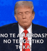 donald trump is wearing a suit and tie and making a funny face while talking into a microphone .