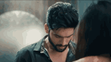 a man with a beard is standing next to a woman and looking down at her .