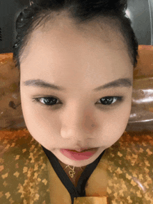 a close up of a little girl 's face with a necklace that says ' bb ' on it