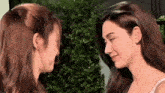 two women are standing next to each other and looking at each other 's faces .