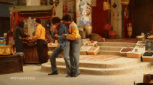 a couple of men are standing next to each other in a market .