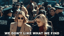 two women are walking in front of a crowd of people with the words we do n't like what we find