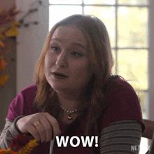 a woman is sitting at a table with a knife and fork and says wow .