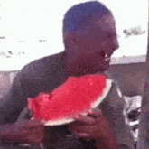 a man is eating a slice of watermelon with a knife .