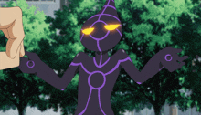 a cartoon character with yellow eyes and a purple body is being held by someone 's hand