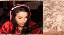 a woman wearing headphones and a red robe is sitting in front of a microphone in a room .