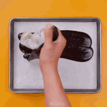 a person is holding a piece of wax paper over a tray of chocolate