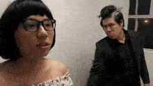 a woman wearing glasses and a man in a suit are standing next to each other