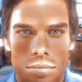 a close up of a man 's face with a blue shirt
