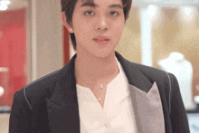 a man wearing a black jacket and a white shirt is looking at the camera