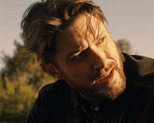 a close up of a man 's face with a beard and a black shirt