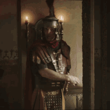 a man in armor stands in front of a wall with candles