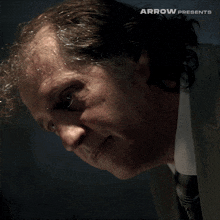 a close up of a man 's face with the words arrow presents above him