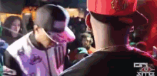 a man in a red hat is talking to another man in a crowd ..