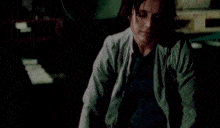 a woman in a blue shirt and grey jacket looks up